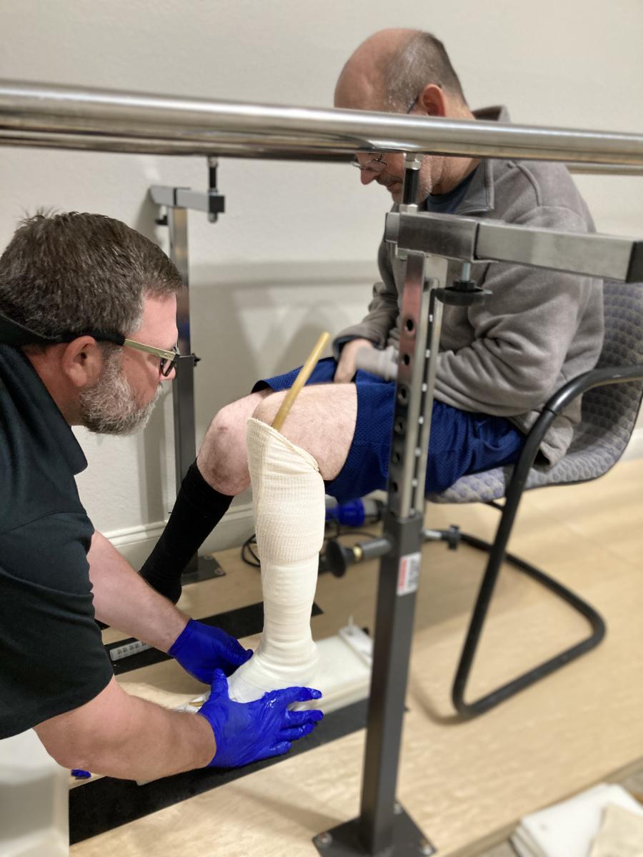 Male clinician measuring and casting a man for a lower leg AFO brace 