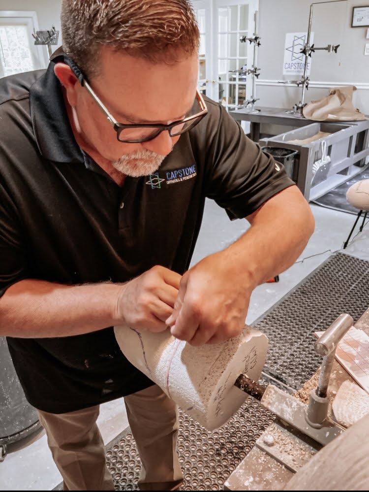 Male clinician using a tape measure to measure a below knee prosthetic mold