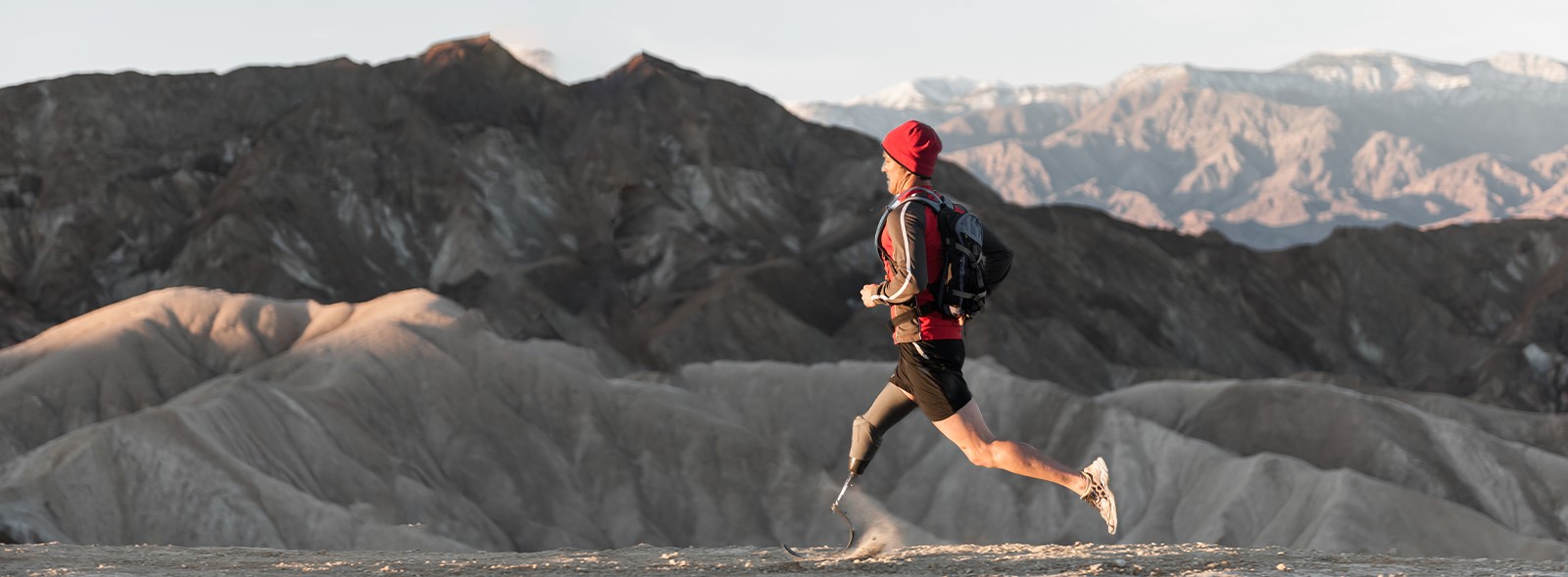Man with prosthetic leg running in the mountains at sunrise
