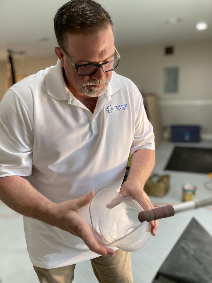 Male clinician smoothing a below knee check socket on the trautman rotating sander